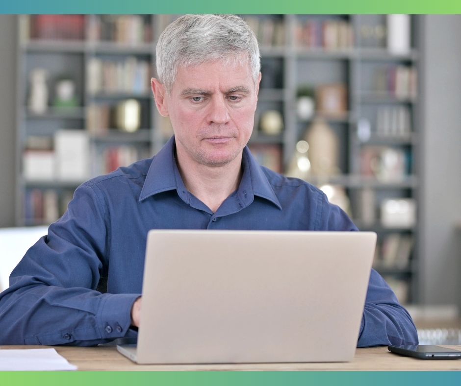 A man in his late 50s reviews results on his laptop at home, thinking about what a blood test might reveal.